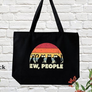 May include: Black tote bag with a retro sunset graphic and black cats. The text "EW, PEOPLE" is printed below the graphic.