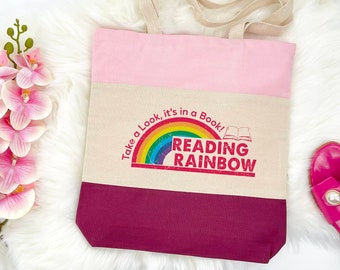 May include: A pink, beige, and burgundy tote bag with a rainbow and the text "Take a Look, it's in a Book! Reading Rainbow" printed on the front.