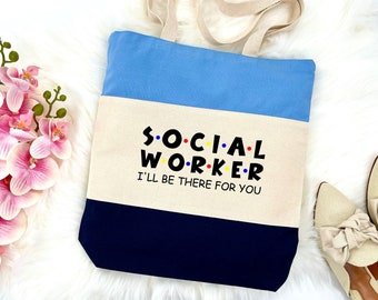 May include: A blue, beige, and navy blue canvas tote bag with the text "SOCIAL WORKER I'LL BE THERE FOR YOU" in black and colorful dots.