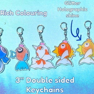 May include: Five 3-inch double-sided keychains featuring colorful cartoon fish with glitter holographic shine. The keychains are attached to silver rings.