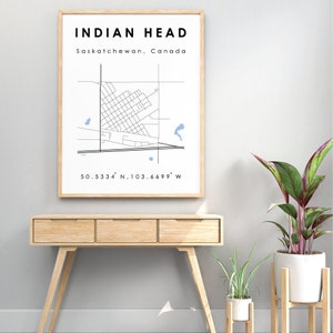 May include: A framed print of a map of Indian Head, Saskatchewan, Canada. The map shows the town's streets and landmarks. The coordinates 50.5334° N, 103.6699° W are printed below the map.