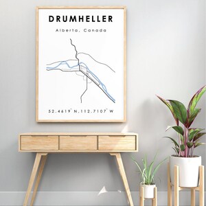 Könnte beinhalten: Ein gerahmter Druck einer Karte von Drumheller, Alberta, Kanada. Die Karte zeigt die Straßen der Stadt und den Red Deer River. Die Koordinaten 52.4619° N, 112.7107° W sind unter der Karte gedruckt.