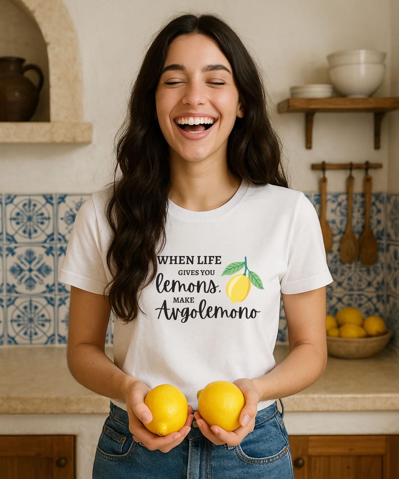 Puede incluir: Una camiseta blanca de manga corta con el texto en negro "WHEN LIFE GIVES YOU lemons. MAKE Avgolemono" y un gr&aacute;fico de un lim&oacute;n amarillo con hojas verdes. La prenda cuenta con un cuello redondo est&aacute;ndar y est&aacute; hecha de tela de algod&oacute;n.