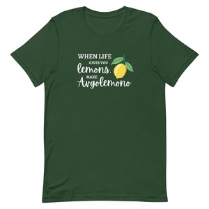 Puede incluir: Una camiseta de manga corta en color verde bosque oscuro con un gr&aacute;fico de un lim&oacute;n amarillo con hojas verdes. El texto impreso en blanco dice: WHEN LIFE GIVES YOU lemons, MAKE Avgolemono. El dise&ntilde;o est&aacute; centrado en el pecho de la camiseta.