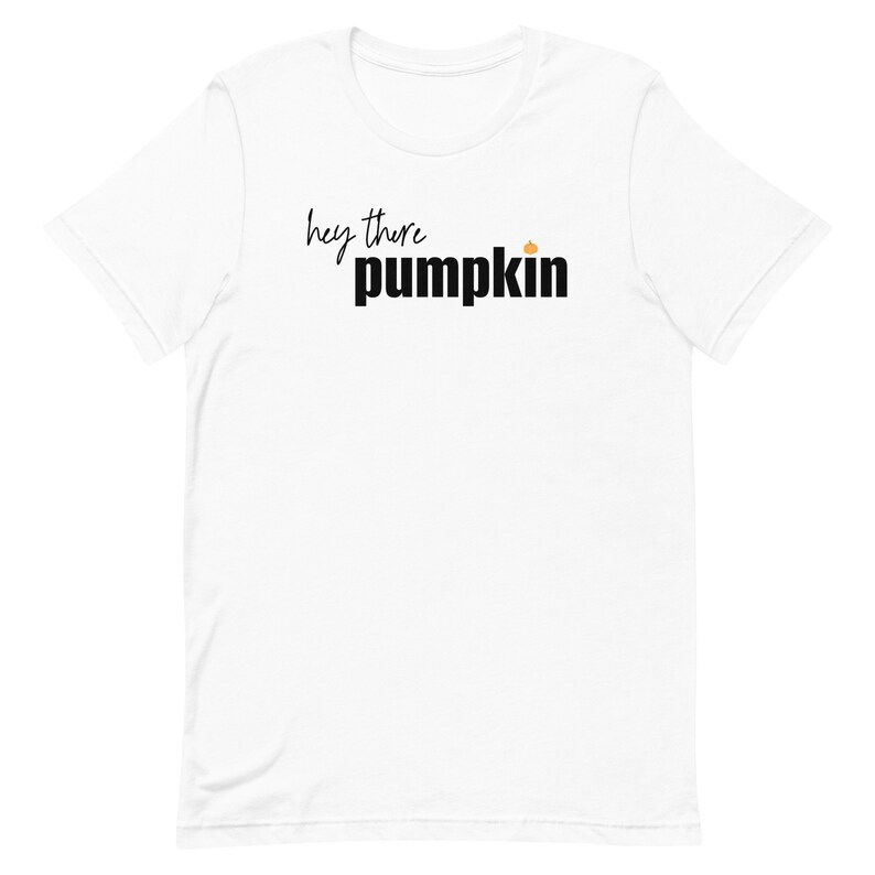 Pode incluir: Camiseta branca com a frase "hey there pumpkin" em preto, em escrita cursiva e letras de bloco, com um pequeno gr&aacute;fico de ab&oacute;bora laranja. Uma pe&ccedil;a casual.