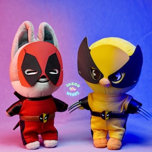 Puede incluir: Dos peluches vestidos como superhéroes. El primer juguete es un conejito blanco que lleva un disfraz de Deadpool rojo y negro. El segundo juguete es un conejito amarillo que lleva un disfraz de Wolverine amarillo y negro. Ambos juguetes tienen máscaras negras en los ojos.