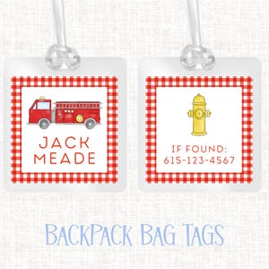 May include: Two square backpack bag tags with a red and white gingham border. One tag features a red fire truck and the name "JACK MEADE". The other tag has a yellow fire hydrant and a phone number.