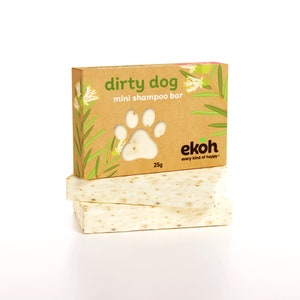 May include: A brown cardboard box with a green paw print and the text "dirty dog mini shampoo bar" and "ekoh every kind of happy" on it. The box is sitting on top of two white bars of soap.