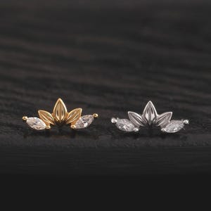 Può includere: Due piccoli orecchini a lobo a forma di ventaglio o corona. Uno è in metallo dorato con due pietre trasparenti taglio marquise sui lati, l'altro è in metallo argentato con due pietre trasparenti taglio marquise sui lati.