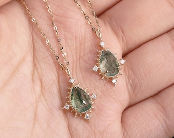 May include: Two gold necklaces with green and white teardrop pendants. Each pendant is surrounded by a halo of smaller white stones.
