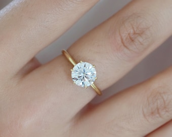 May include: A gold band engagement ring with a large, round, clear diamond.