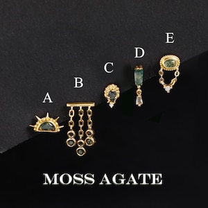Pode incluir: Cinco brincos de ouro rotulados de A a E com pedras de ágata musgo. O brinco A tem um design de sol, B tem três correntes pendentes, C tem formato de coração, D é uma barra vertical e E é oval com uma corrente pendente. Texto: MOSS AGATE.