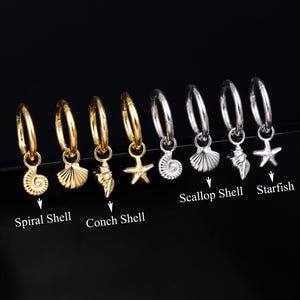 May include: Eight hoop earrings featuring dangling charms in gold and silver tones. The charms include spiral shells, scallop shells, conch shells, and starfish. Text labels identify the specific shell and starfish designs below the charms.