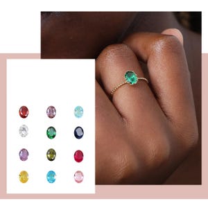 Puede incluir: Un anillo de oro con una banda de cuentas y una piedra preciosa ovalada verde.