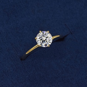 May include: A gold engagement ring with a round, clear diamond.