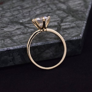 May include: A gold engagement ring with a large, clear, round-cut diamond.