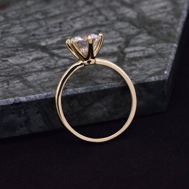 May include: A gold engagement ring with a large, clear, round-cut diamond.