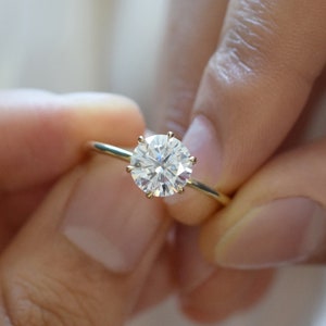 May include: A gold engagement ring with a large, round, clear diamond.