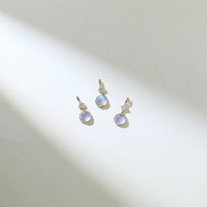 May include: Three gold pendants with a round, iridescent moonstone and a small, clear diamond accent.