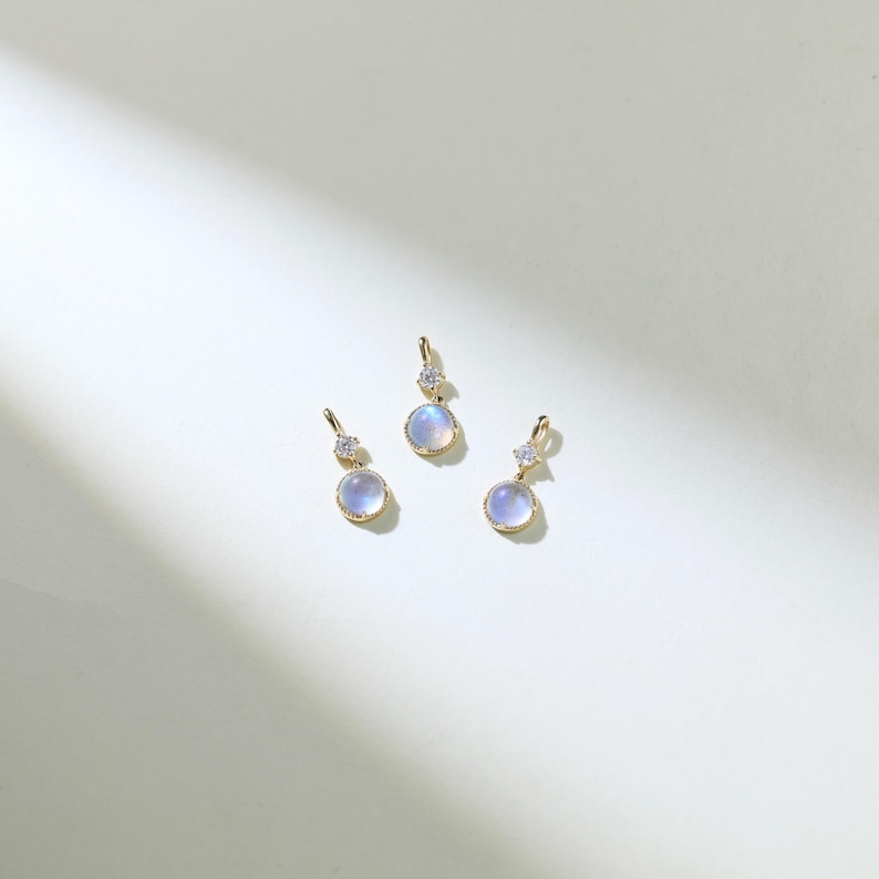 May include: Three gold pendants with a round, iridescent moonstone and a small, clear diamond accent.