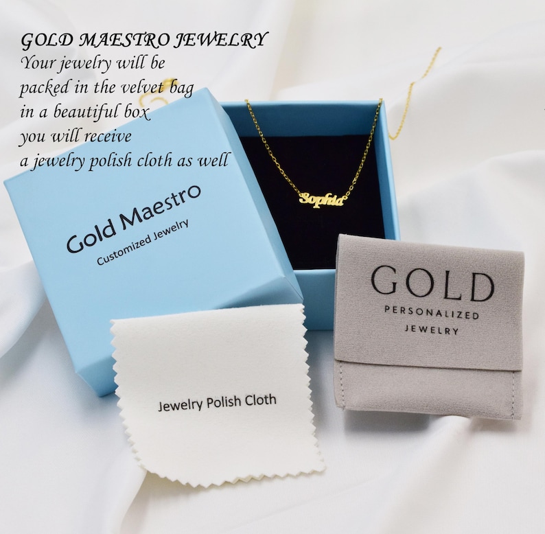 May include: A light blue box with the text "Gold Maestro Jewelry" and "Customized Jewelry". The box contains a gold necklace with the name "Sophia" on it. The necklace is in a gray velvet pouch with the text "Gold Personalized Jewelry". A white cloth with the text "Jewelry Polish Cloth" is in front of the box.