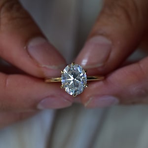 May include: A gold ring with a large, oval-shaped diamond.