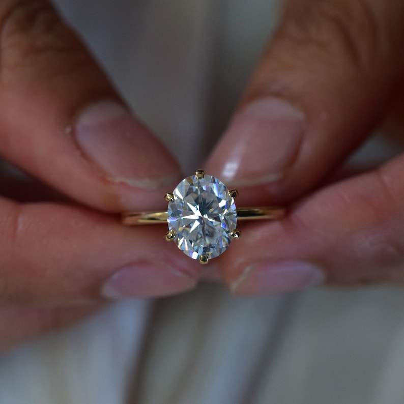 May include: A gold ring with a large, oval-shaped diamond.