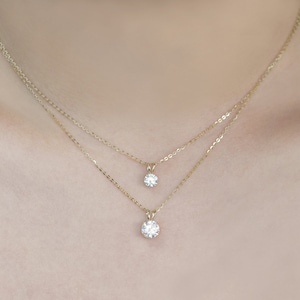 Pu&ograve; includere: Due delicate collane d'oro, ciascuna con un singolo pendente rotondo in pietra preziosa trasparente. Le collane sono a strati, con un pendente leggermente pi&ugrave; piccolo dell'altro. Le catene e i pendenti hanno una finitura lucida e lucidata.