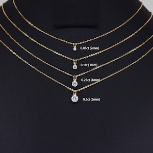 Pu&ograve; includere: Quattro collane d'oro con pendenti di diamanti di varie dimensioni sono esposte su sfondo nero. I pendenti sono etichettati con il loro peso in carati e le dimensioni in mm: 0,03 ct (2 mm), 0,1 ct (3 mm), 0,25 ct (4 mm) e 0,5 ct (5 mm).