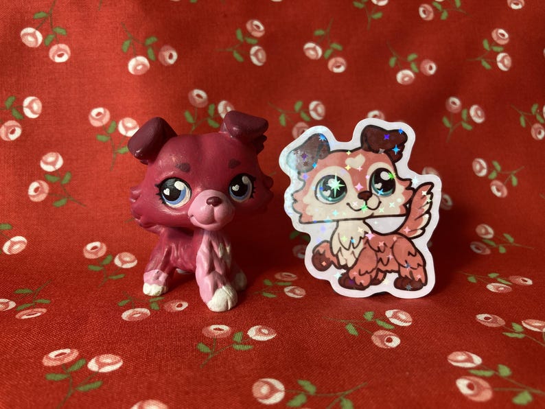 May include: Two pink and white dog figurines. One is a 3D printed figurine and the other is a sticker. Both dogs have sparkly eyes.