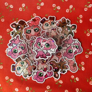 May include: A collection of colorful, glittery stickers featuring cartoon dogs and cats. The stickers are on a red background with white flowers.