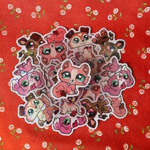 May include: A collection of pink and brown glitter stickers featuring cartoon animals with large eyes. The stickers are arranged in a circle on a red background with white flowers.