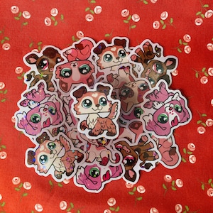 May include: A collection of colorful, glittery stickers featuring cartoon animals. The stickers are mostly pink and white with some brown and black accents. The animals include dogs, cats, and other creatures.
