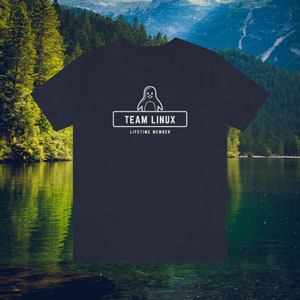 Pode incluir: Camiseta azul marinho com um desenho branco de um pinguim acima do texto "TEAM LINUX" e "LIFETIME MEMBER". O design está centrado na frente. A camiseta é feita de um material macio.