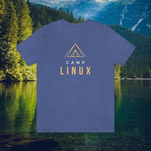 May include: Blue t-shirt featuring the words "CAMP LINUX" in gold, with a gold tent graphic above. The tee shirt is made of a soft material, suitable for casual wear or outdoor activities.