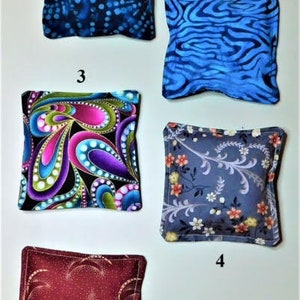 May include: Five different fabric squares with various patterns. The squares are numbered 1 through 5. Square 1 is blue with white dots. Square 2 is blue with a wavy pattern. Square 3 is black with pink, green, and purple swirls. Square 4 is gray with a floral pattern. Square 5 is burgundy with a white pattern.