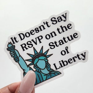 May include: A white sticker with a blue and green illustration of the Statue of Liberty holding a torch. The sticker says "It Doesn't Say RSVP on the Statue of Liberty".
