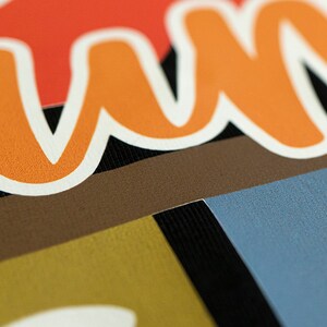 May include: Close-up of a colorful fabric with the word "Summer" written in orange and white letters.