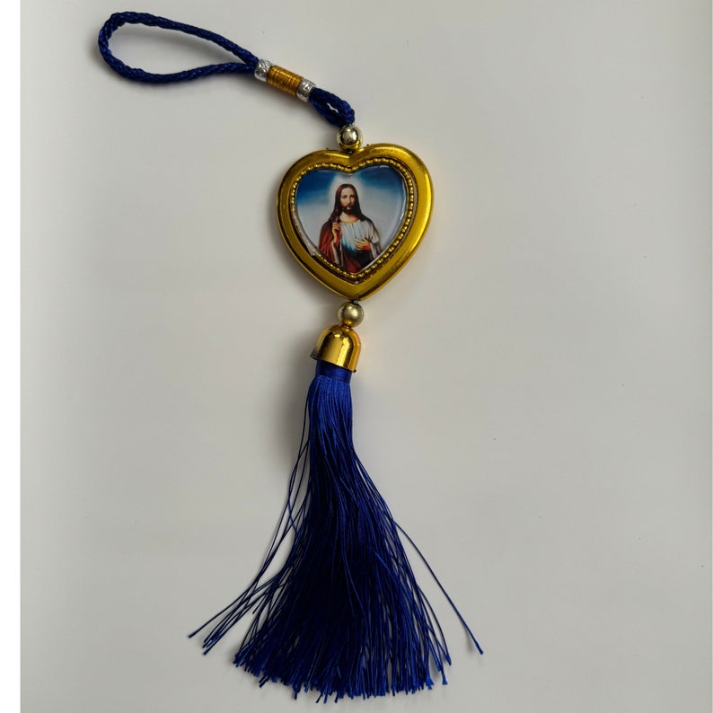 May include: A gold heart-shaped charm with a picture of Jesus inside. The charm is attached to a blue tassel.