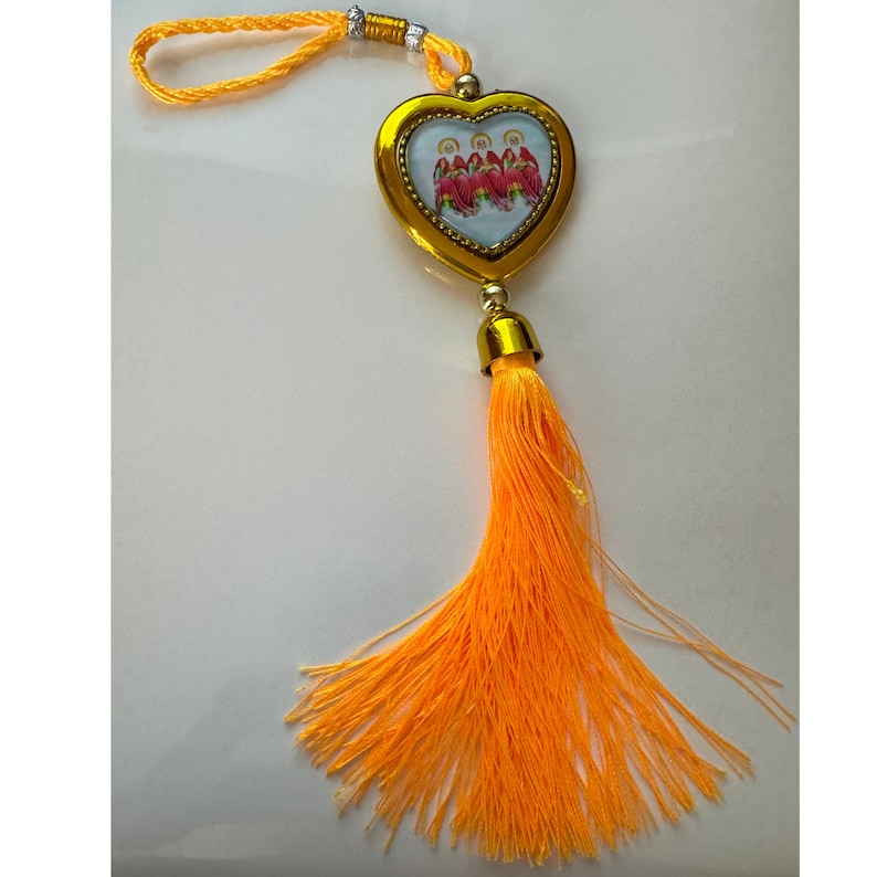 May include: A gold heart-shaped charm with a picture of four people inside. The charm is attached to a yellow tassel.