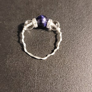 May include: A silver ring with a blue gemstone and clear crystal beads.