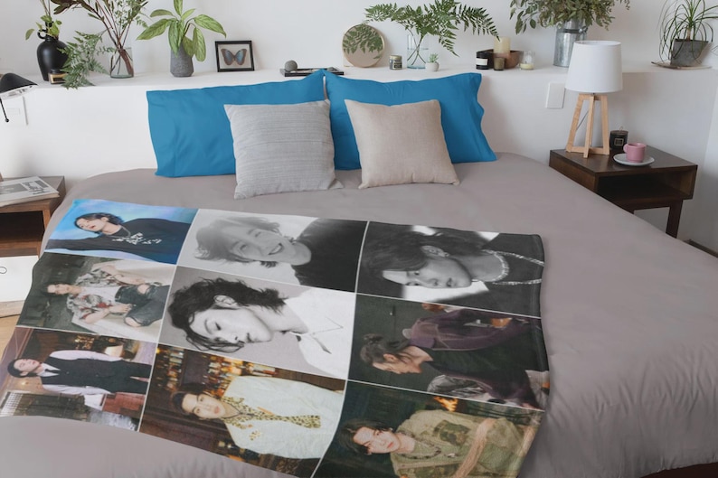 May include: A blanket featuring a collage of images of a person in various poses and outfits. The blanket is laid out on a bed with blue and beige pillows. The bed is covered with a gray sheet.