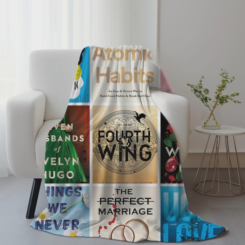 Puede incluir: Una manta blanca con un collage de portadas de libros, incluyendo "Atomic Habits" y "Fourth Wing", sobre un sill&oacute;n blanco. El dise&ntilde;o incorpora varios colores y texto, creando una est&eacute;tica acogedora y literaria.