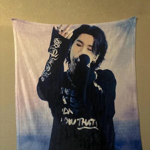 May include: A rectangular tapestry featuring a person singing into a microphone. The person is wearing a black long-sleeved shirt with the text "I SEE DON'T KNOW THAT!" The tapestry has a gradient background of blue, white, and purple.