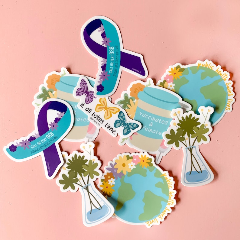 May include: A set of colorful stickers with various designs and messages. The stickers feature illustrations of butterflies, flowers, a globe, and a jar with the text "vaccinated & feinate". Other stickers include the text "it all takes time" and "public health saves lives".