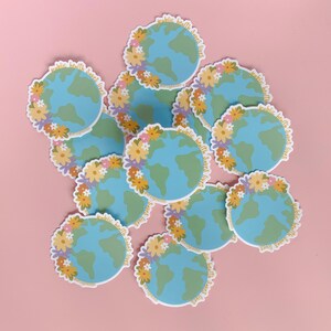 May include: A pile of colorful stickers with a blue and green globe design. The stickers have a floral border and the text "public health saves lives" around the globe.