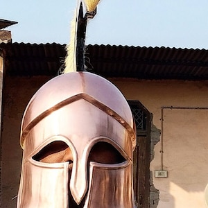 May include: A copper colored Spartan helmet with a plume of white feathers on top.