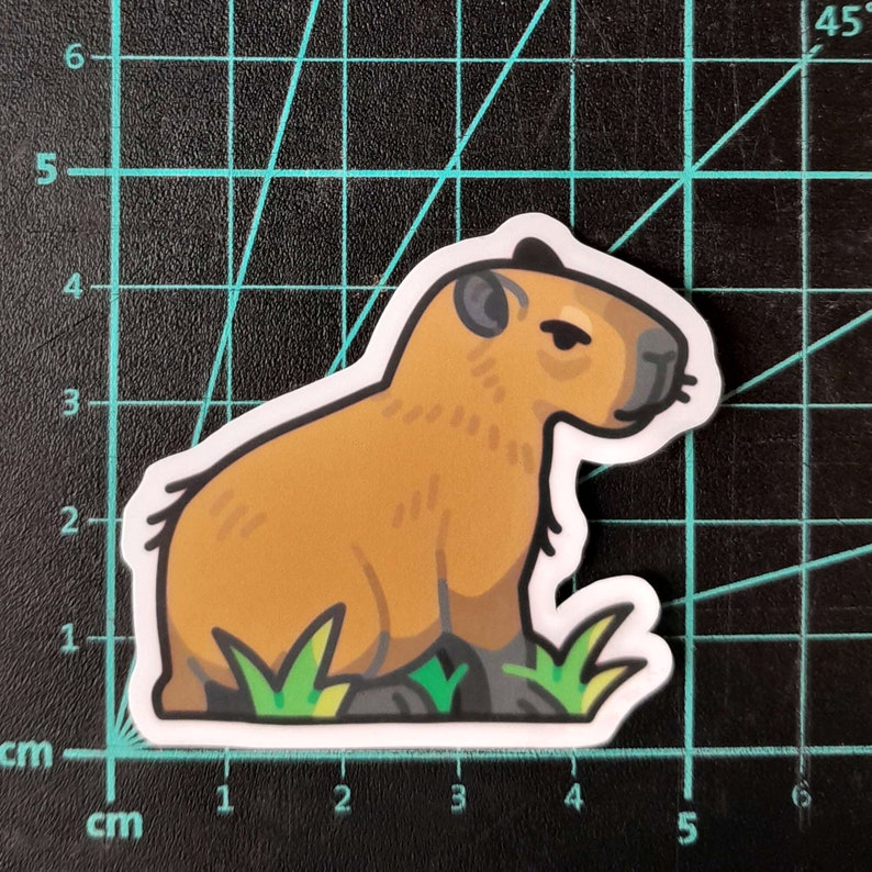 May include: A cartoon illustration of a brown capybara sitting on a patch of green grass. The capybara is facing to the right and has a slightly grumpy expression.