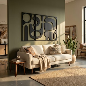 May include: A living room scene featuring a cream-colored sofa with decorative pillows and a fringed throw blanket. A large, black abstract wall art piece hangs above the sofa. A jute rug and a wooden side table complete the cozy, modern aesthetic.