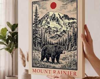 May include: A rectangular wooden wall art piece featuring a black ink illustration of a bear in a meadow with Mount Rainier in the background. A red sun sits above the mountain peaks. The text MOUNT RAINIER is printed in red at the bottom.